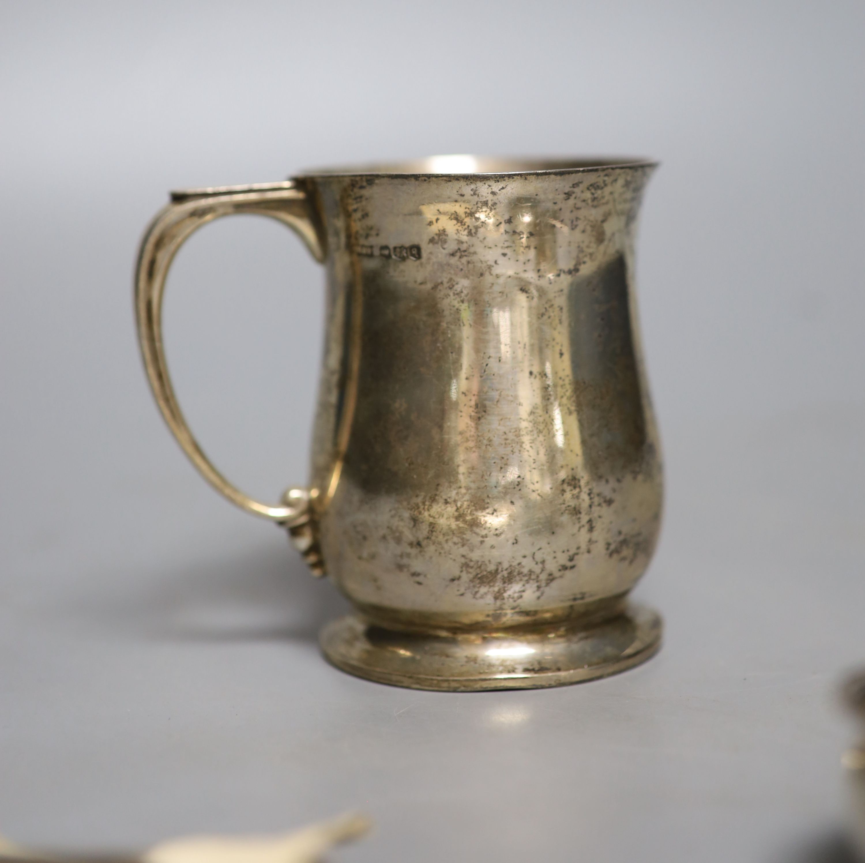 A George V silver mug, a white metal toddy ladle bowl, an Edwardian silver trinket box, a silver reproduction Roman spoon and a George III 'Sherry' label.